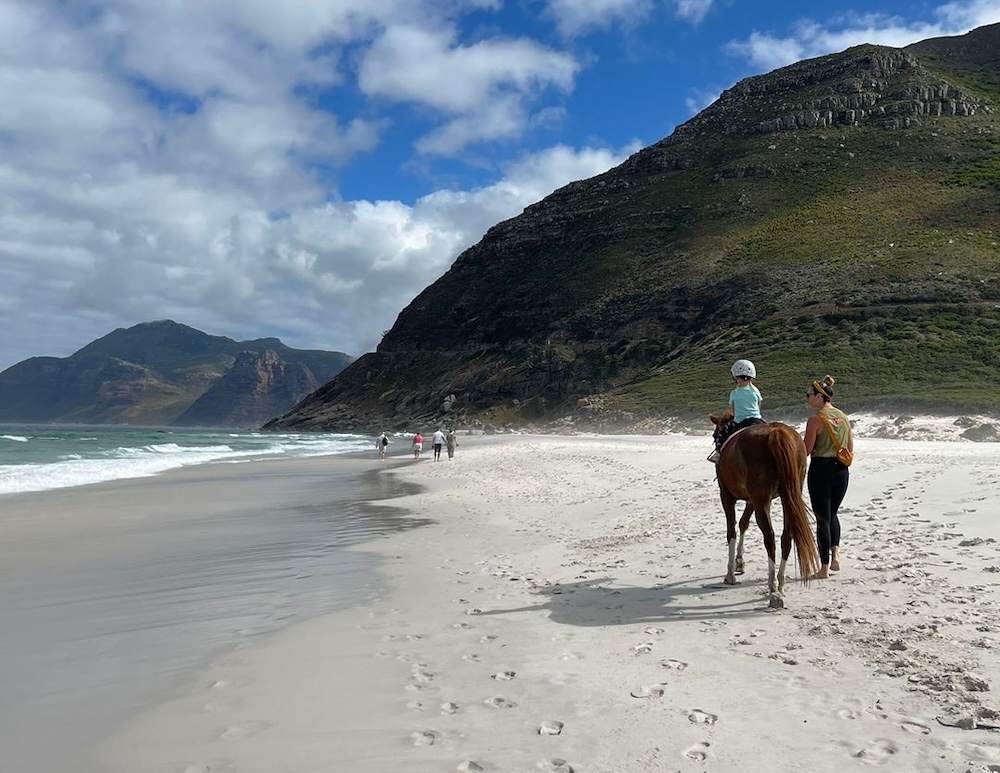 Walking through waves on a Noordhoek beach ride